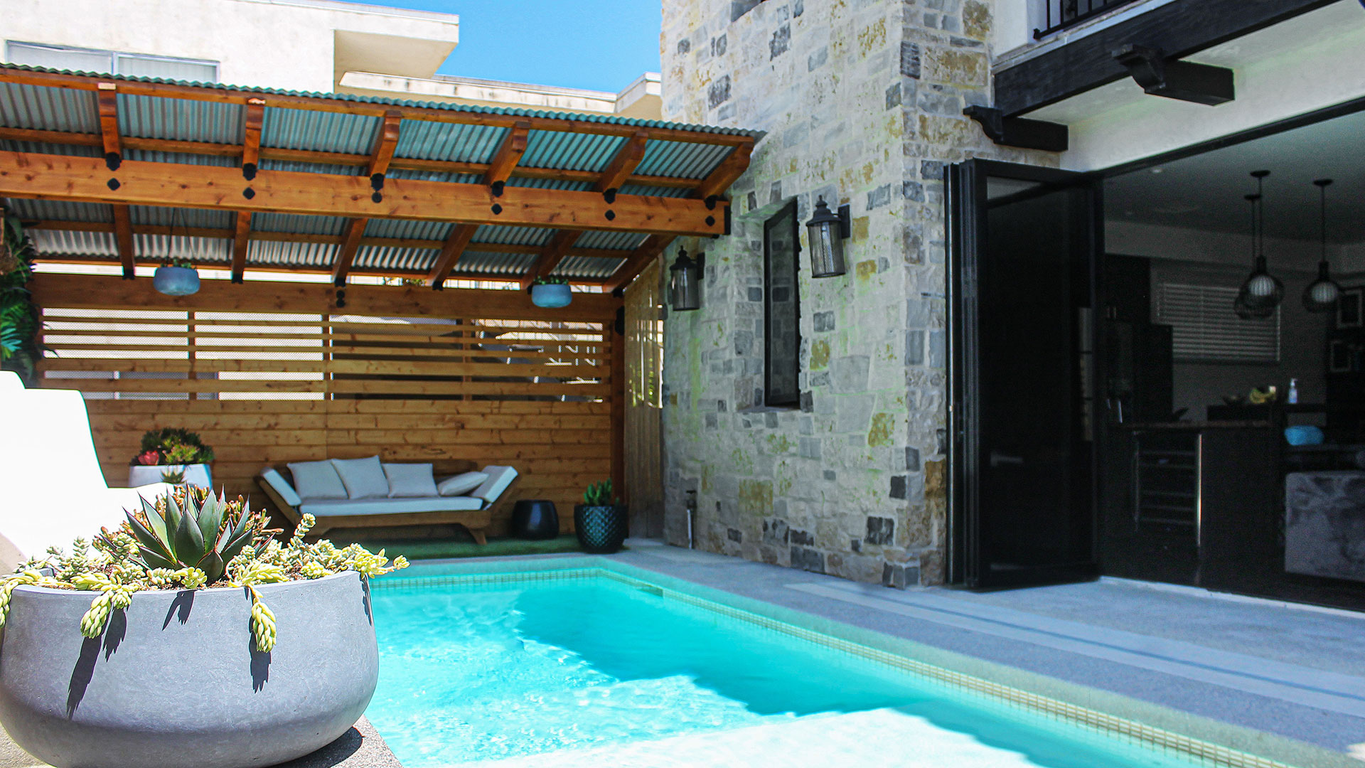 Pool with seating area backyard with Cottage Cream rubble natural stone thin veneer with overgrout installed on exterior wall