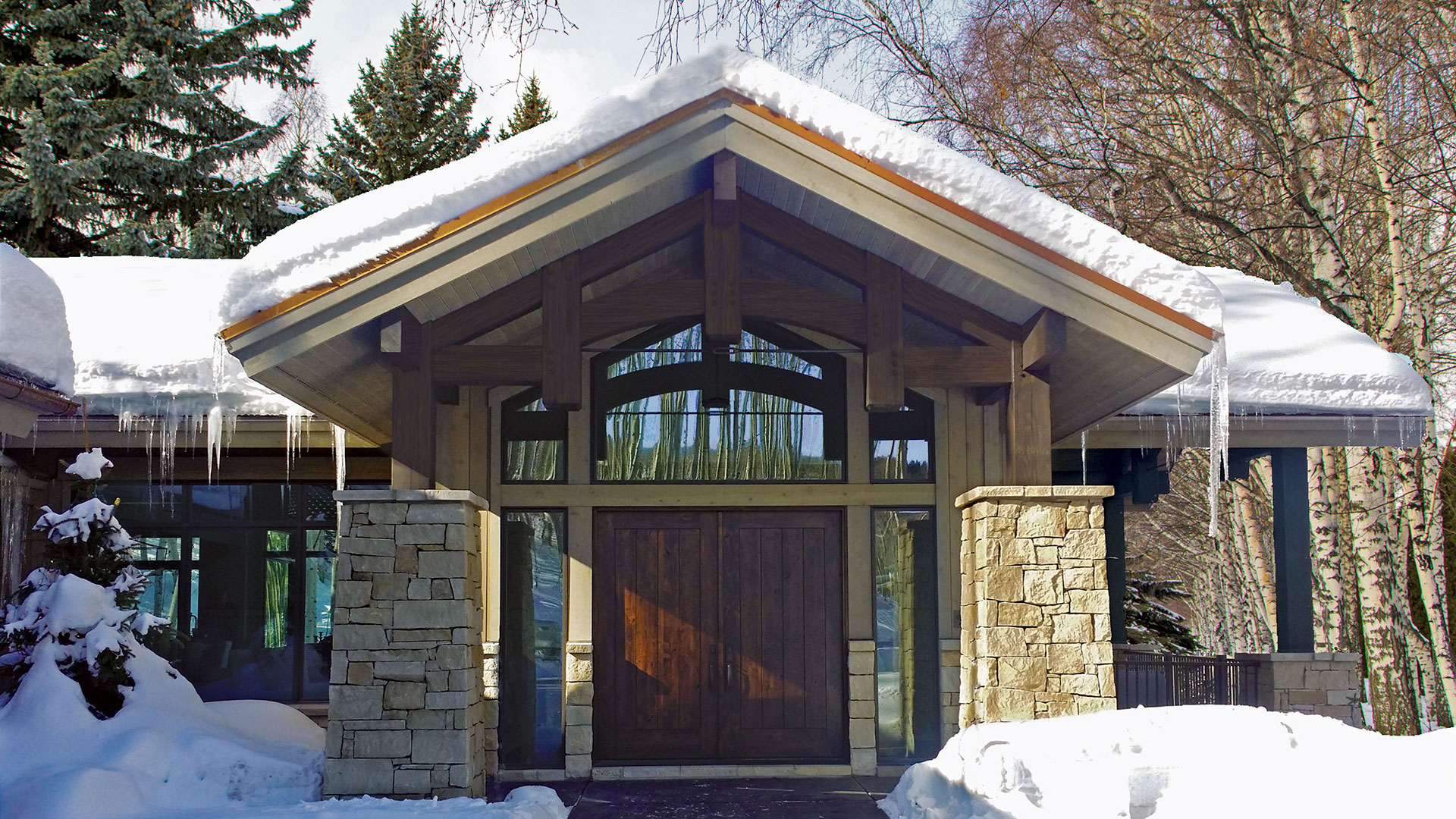 snow covered front of home with Regent Buff rubble natural stone thin veneer installed on exterior walls